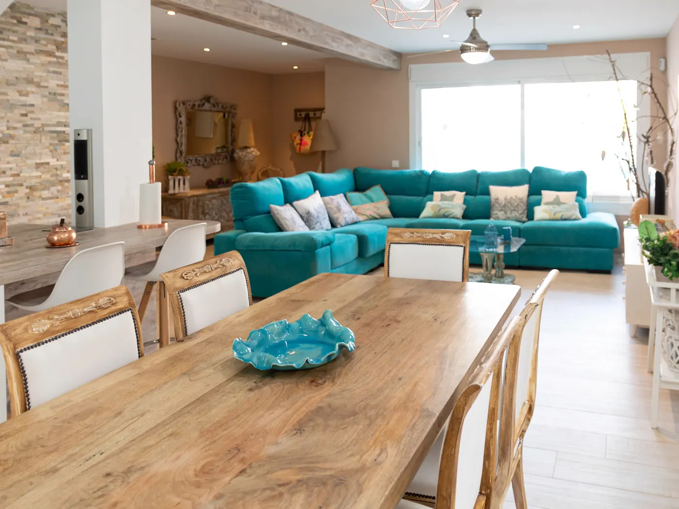 Salón amplio con sofá turquesa y mesa de comedor