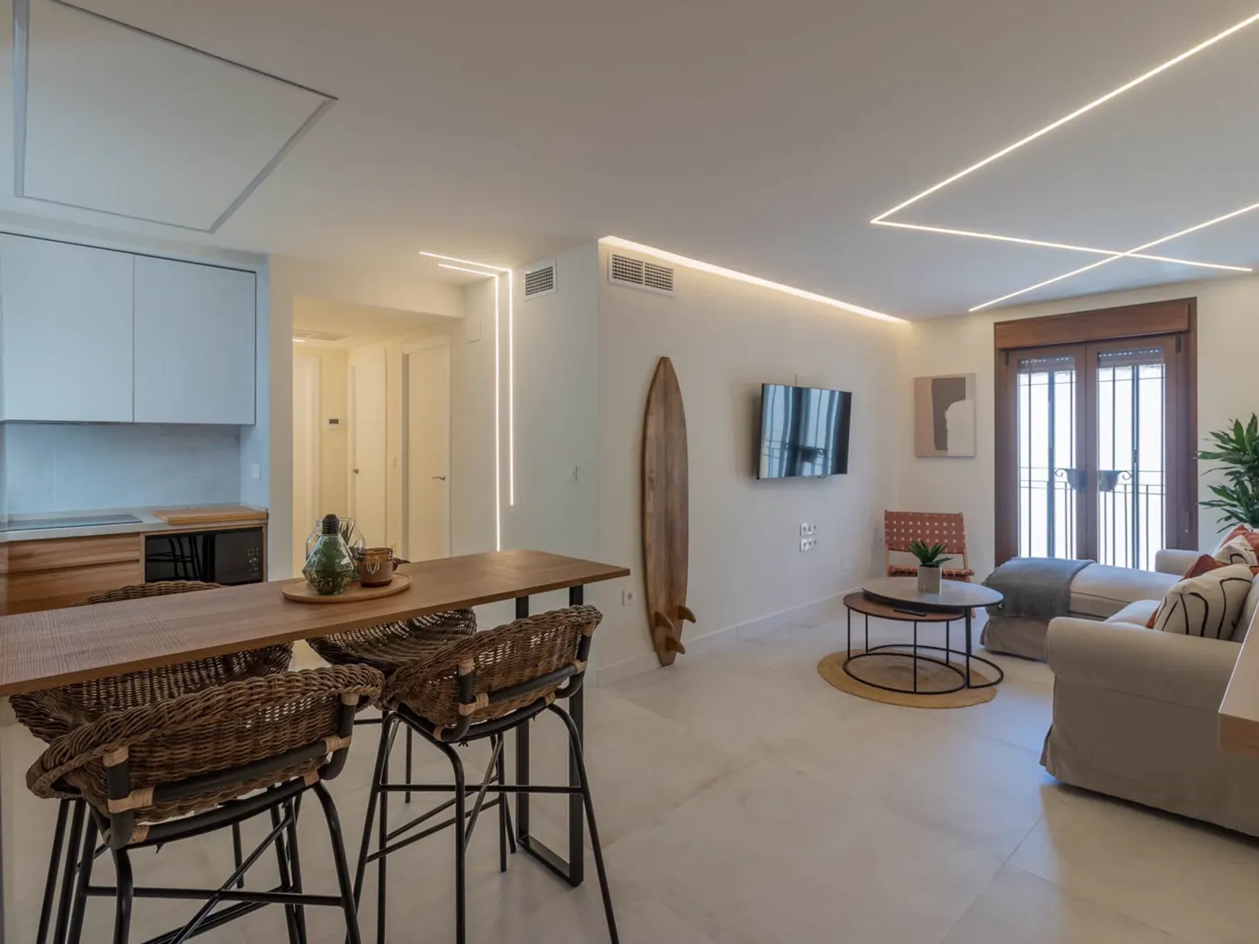 Salón con barra de cocina y taburetes de mimbre