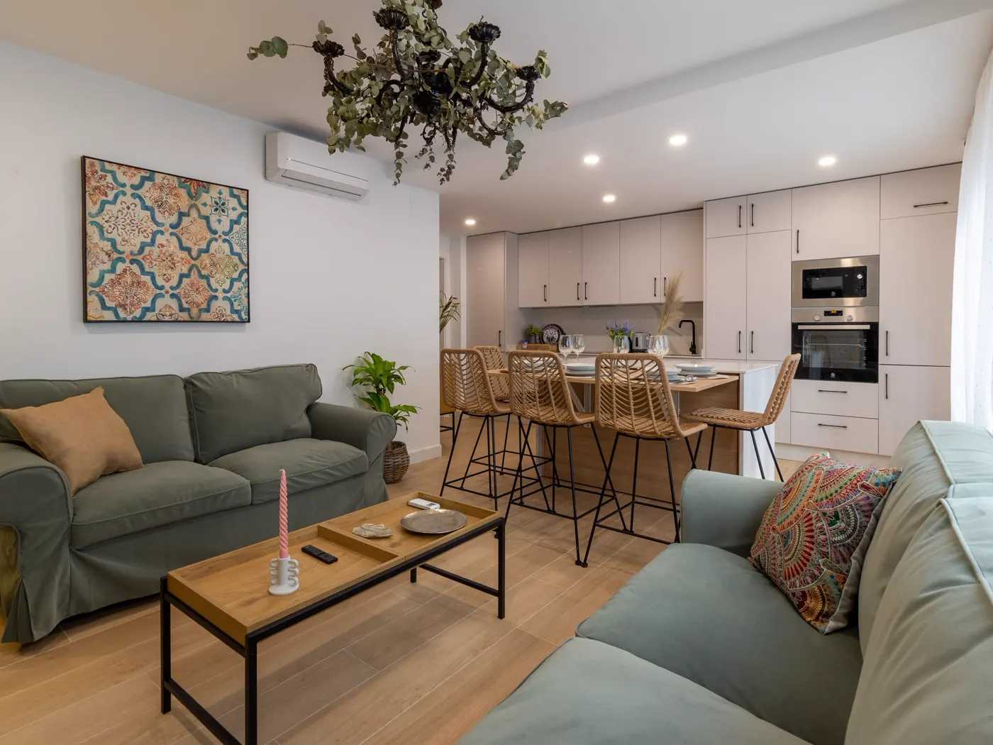 Salón con sofás verdes y cocina integrada